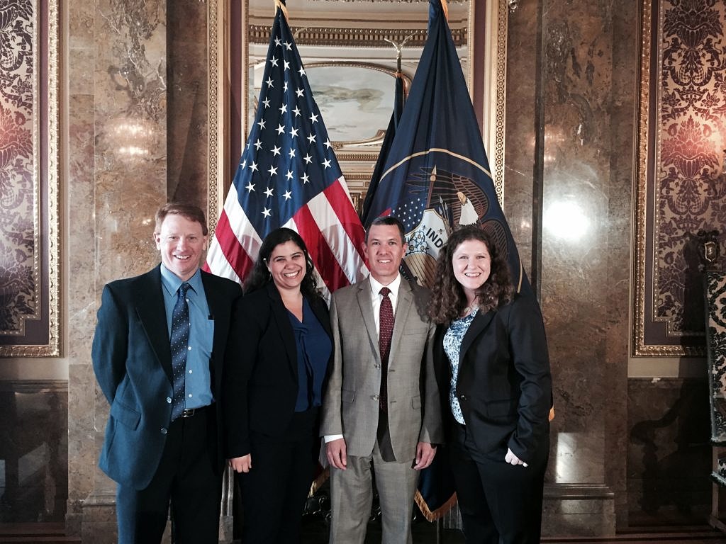 two men and two women standing in front of american and utah flag