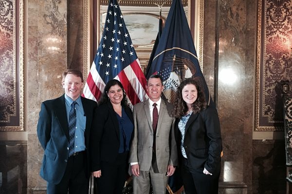 two men and two women standing in front of american and utah flag