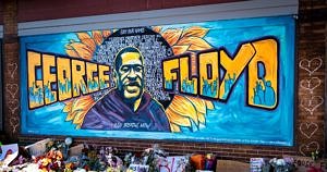 A memorial for Gorge Floyd, including a portrait and flowers on the sidewalk