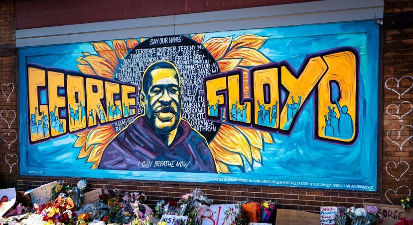 A memorial for Gorge Floyd, including a portrait and flowers on the sidewalk