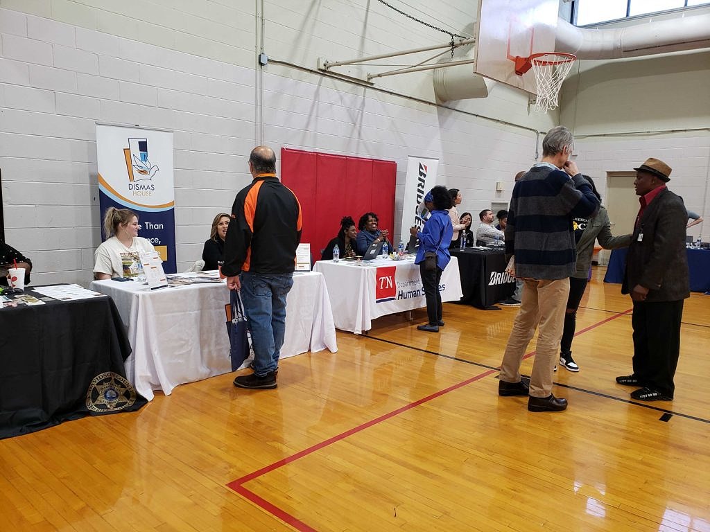 Photo of people in a large room talking in groups or visiting information booths