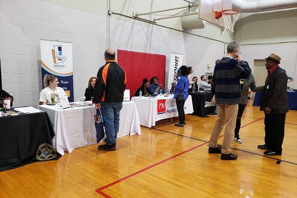 Photo of people in a large room talking in groups or visiting information booths
