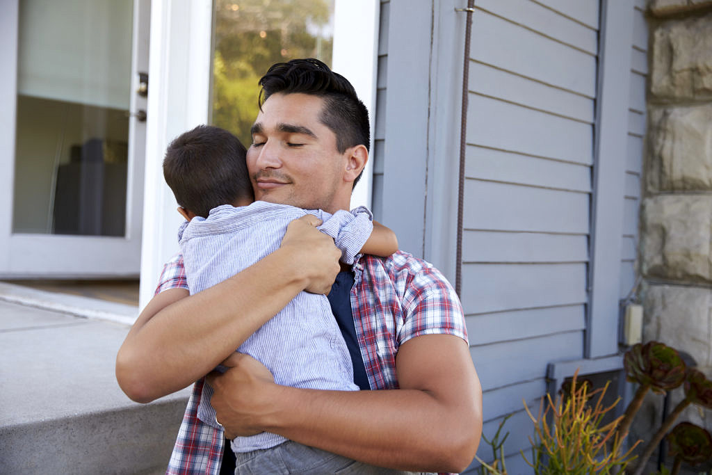 A man smiles while hugging a child