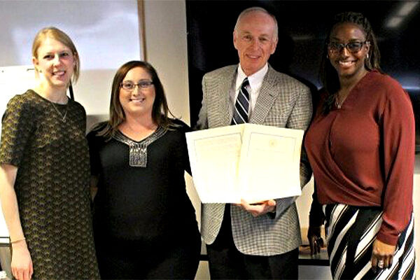 Four people holding paper proclamation