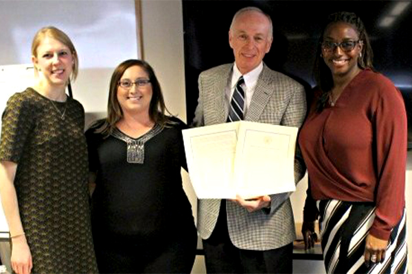 Four people holding paper proclamation