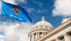 Oklahoma state capitol building against a blue sky. State flag flies in front.