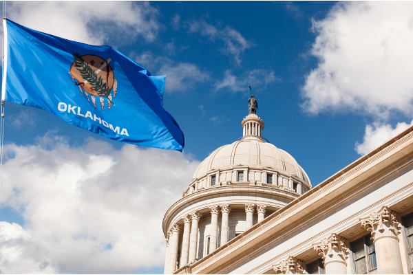 Oklahoma state capitol building against a blue sky. State flag flies in front.